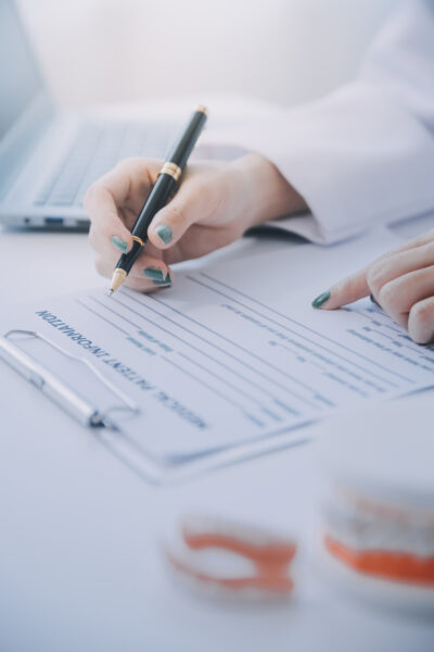 Dentists are discussing dental problems at report x-ray image on laptop screen to patients.